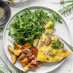 the frittata on a white plate with salad and homefries