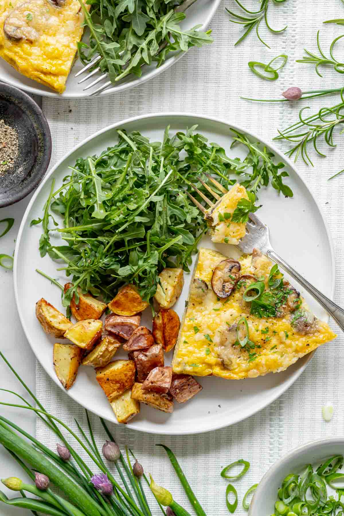 the frittata on a white plate with salad and homefries