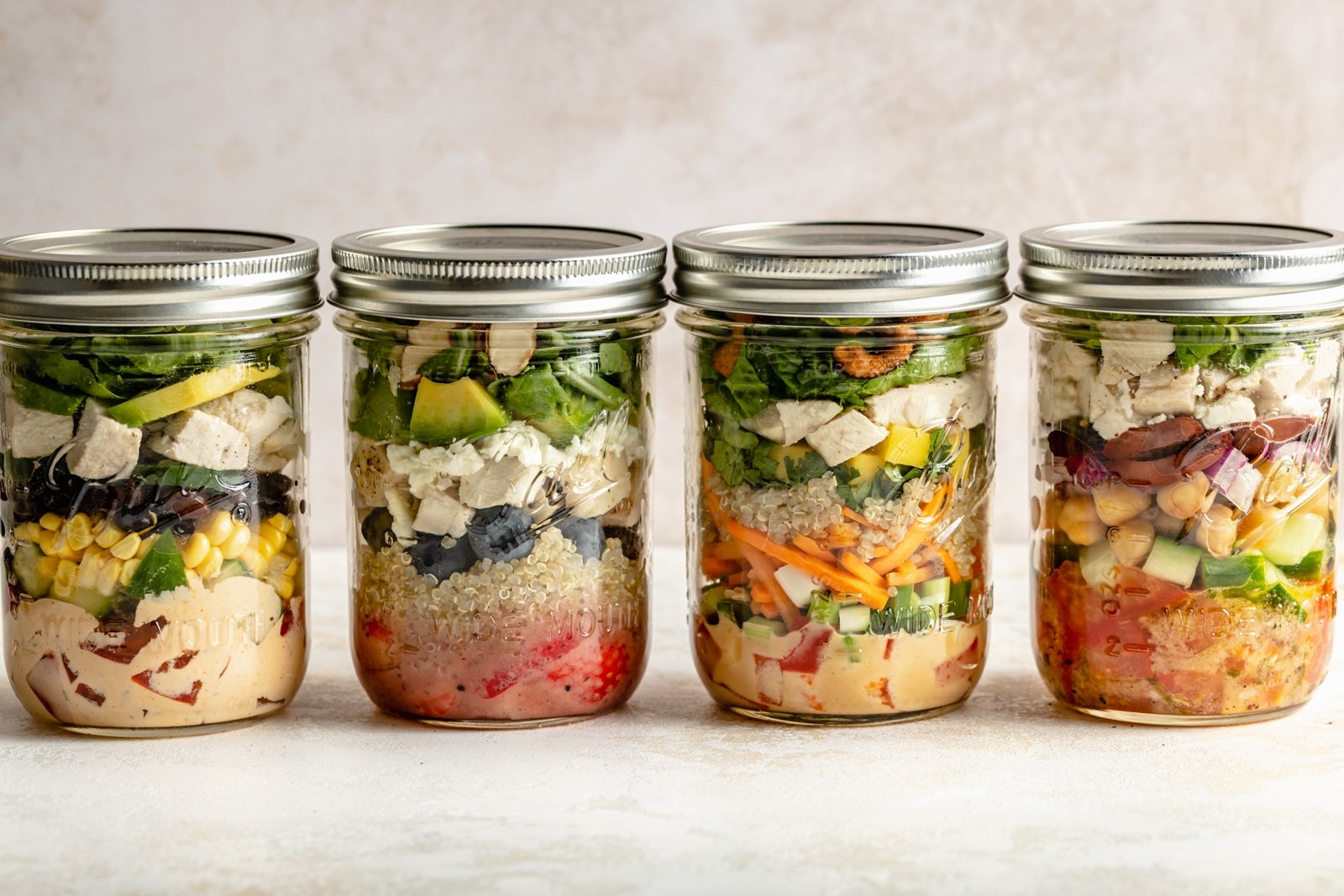 four mason jar salads in a row