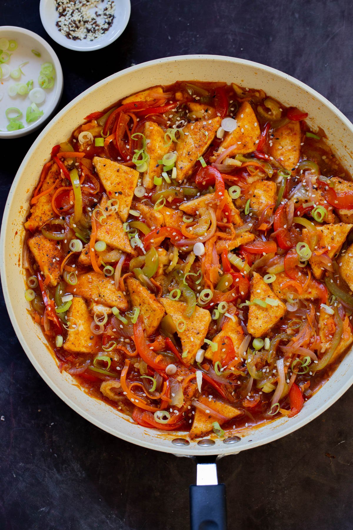 Szechuan tofu in the pan with green onions and sesame seeds