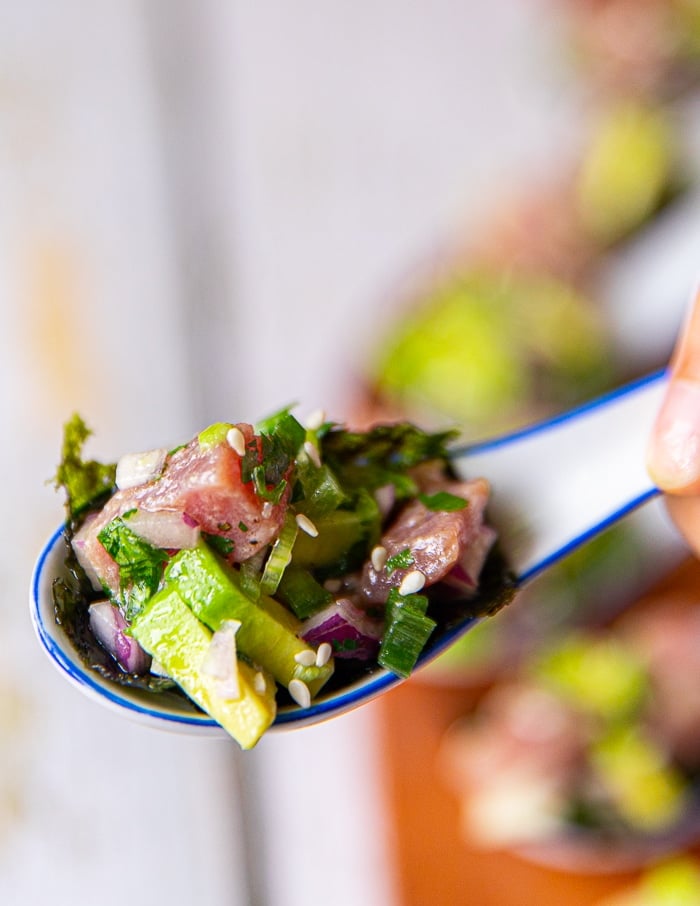 close up of a spoonful of tuna ceviche served as an appetizer with seaweed