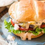 a photo of a cheeseburger with burger sauce dripping down the sides with tomato and lettuce showing