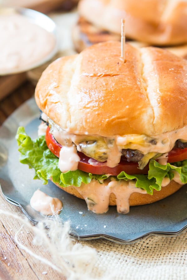 a photo of a cheeseburger with burger sauce dripping down the sides with tomato and lettuce showing