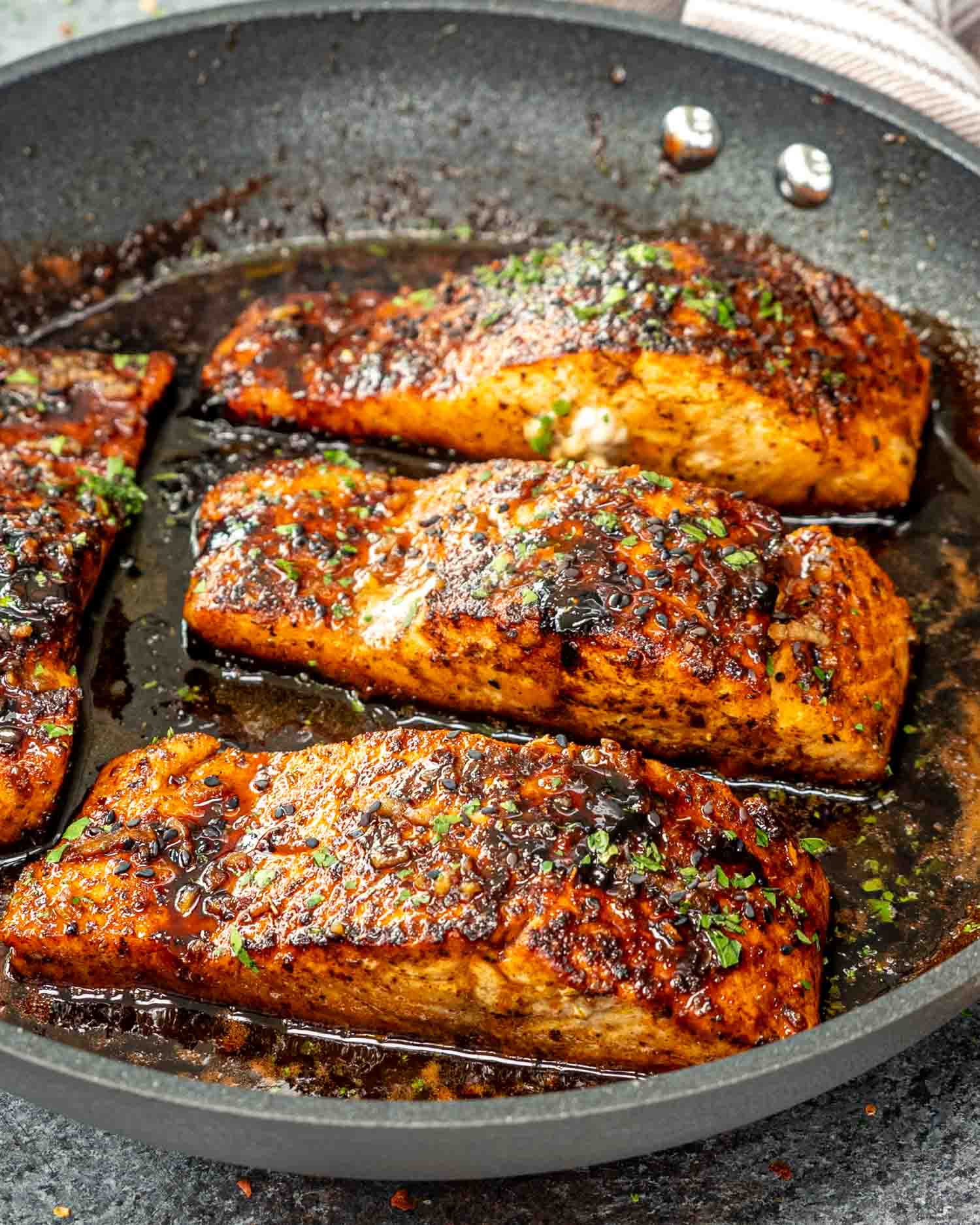 cajun honey butter salmon fillets in a skillet.