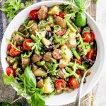 the potato salad on a gray board with a linen towel and large serving spoon