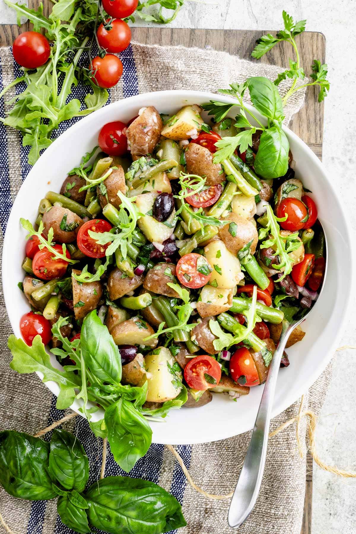 the potato salad on a gray board with a linen towel and large serving spoon