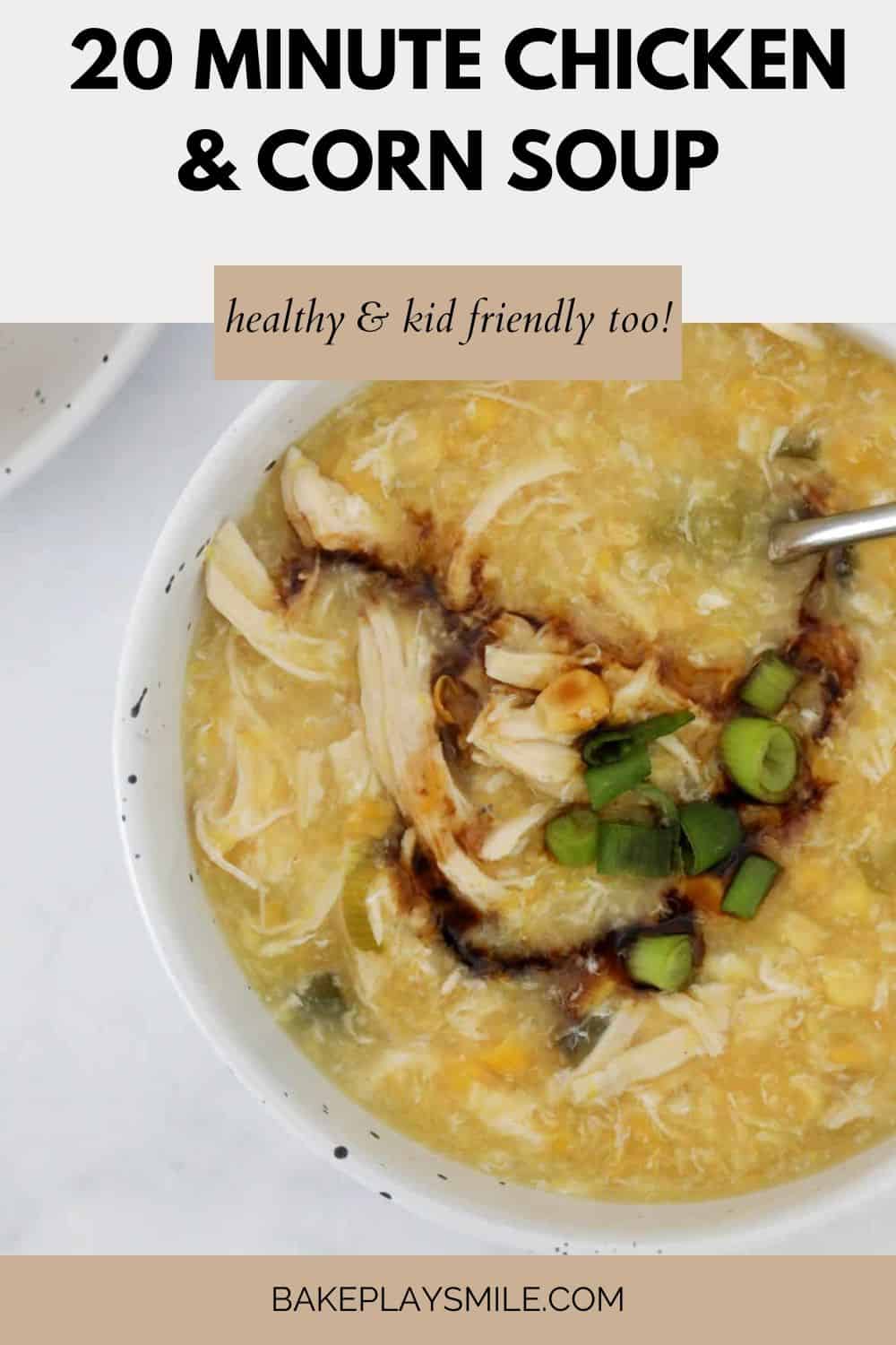 Thick chicken and corn soup in a bowl, with soy sauce and spring onions on top.