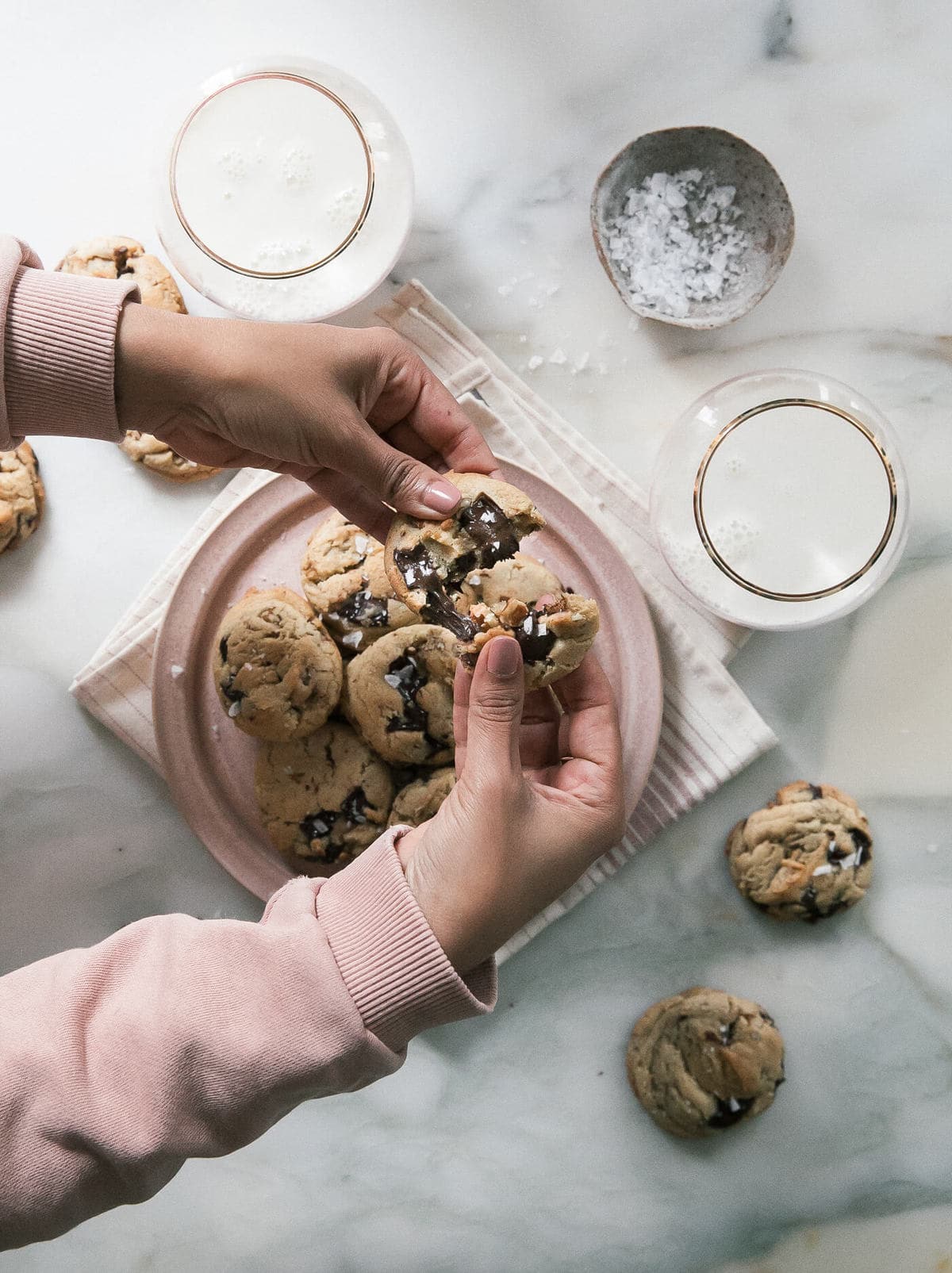 Hands breaking Bourbon Pecan Chocolate Chip Cookies in half.