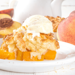 Close up image of crock pot peach cobbler with a scoop of vanilla ice cream