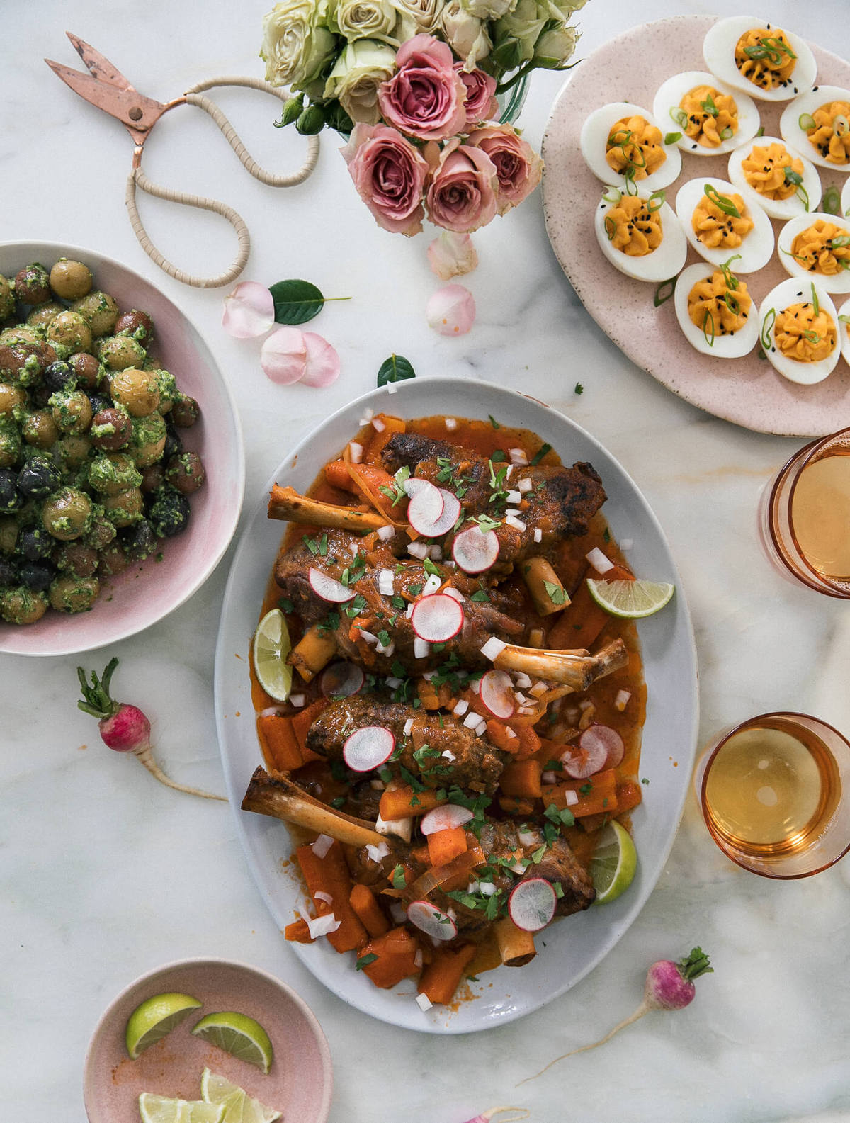 Dinner spread of herby potatoes, deviled eggs, and lamb on serving platter.