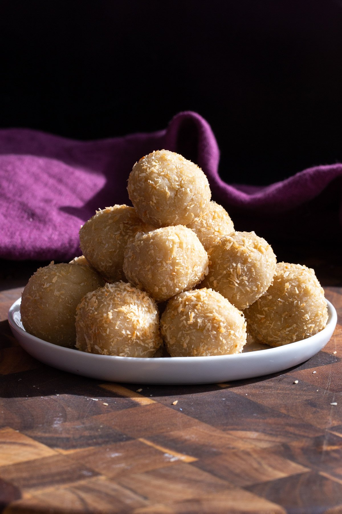 lemon coconut energy bites on a small white plate with a purple napkin in the background