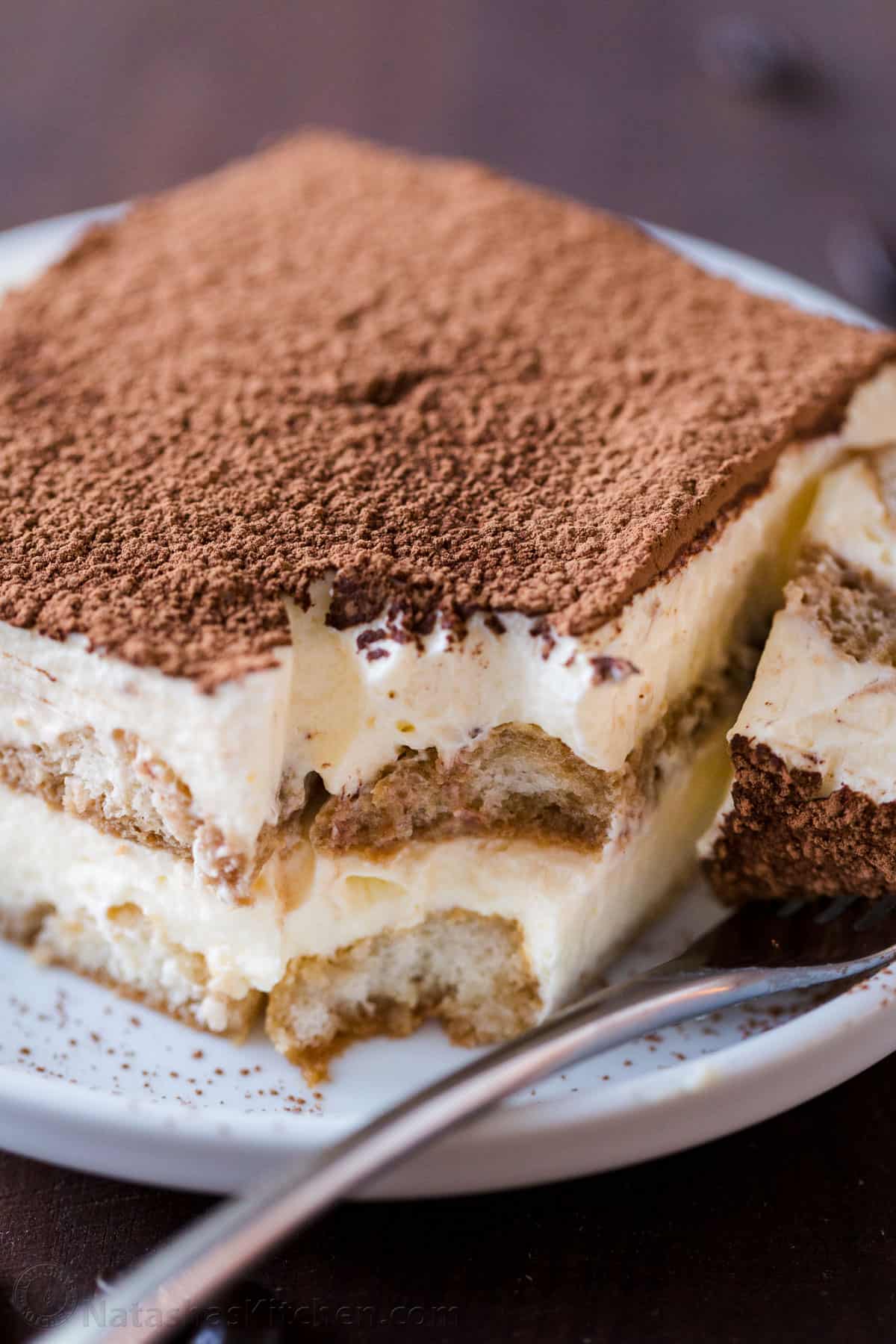 a piece of homemade tiramisu cake on a plate with a fork