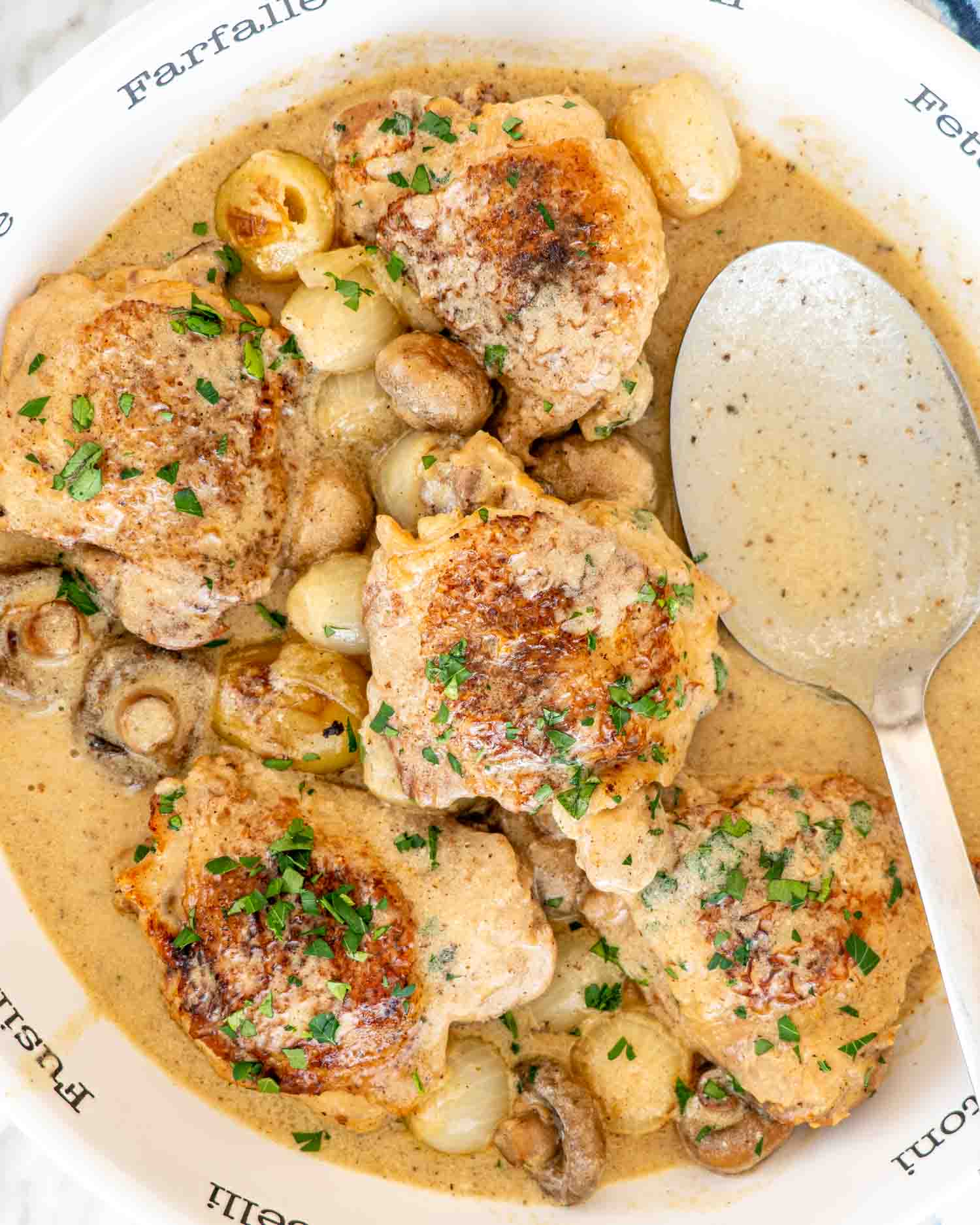 freshly made chicken fricassee in a white serving bowl garnished with parsley.