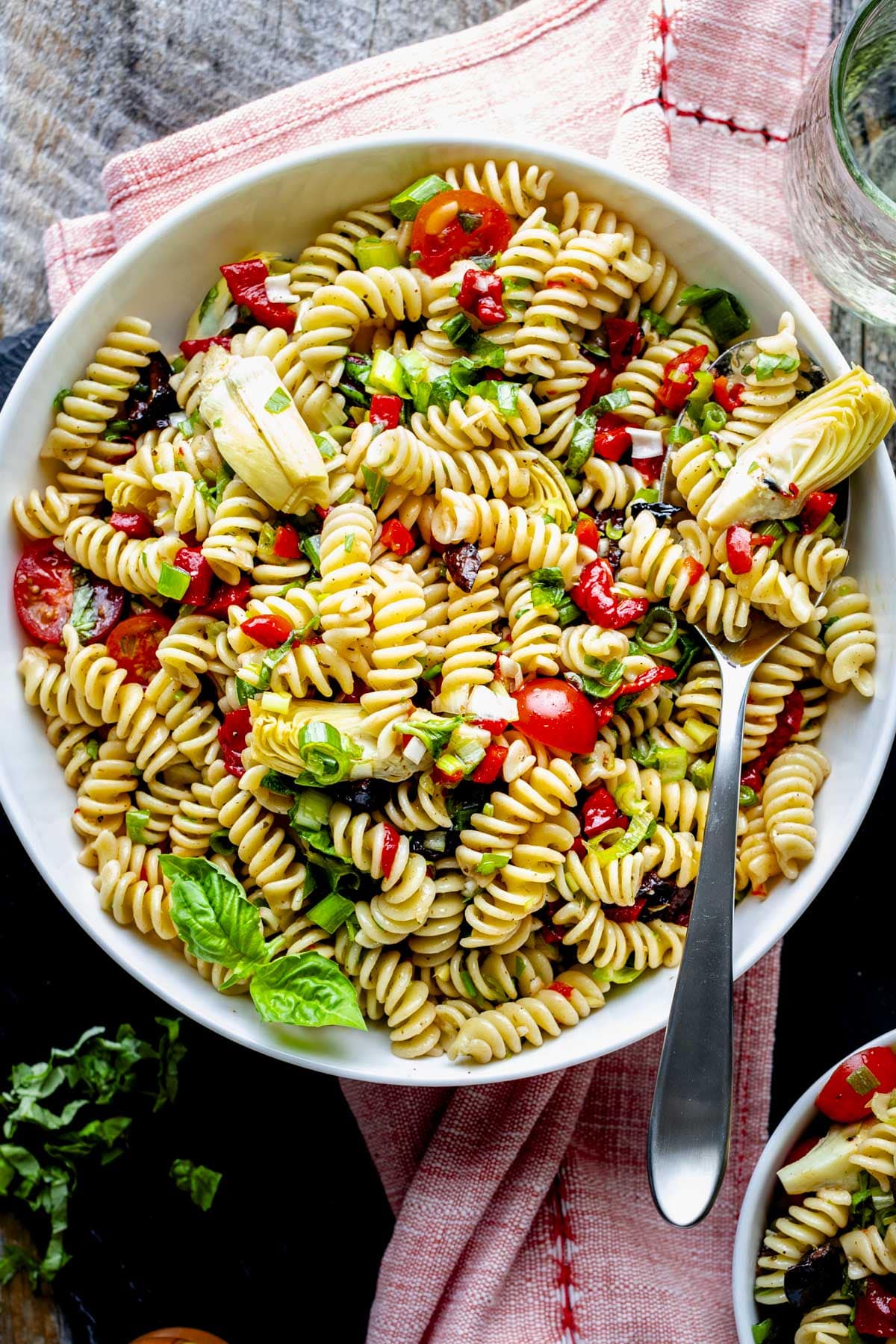 the pasta salad in a white bowl from overhead with a stainless steel serving spoon in it